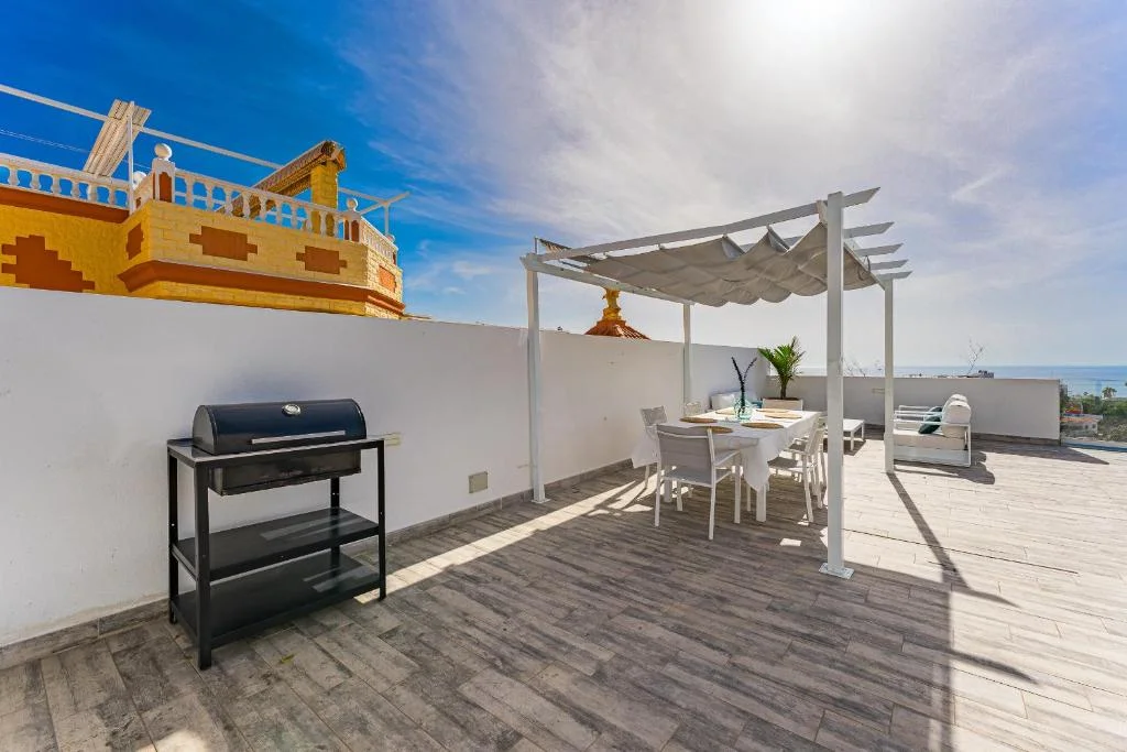 Terrasse mit Grill und Essbereich unter einer Pergola
